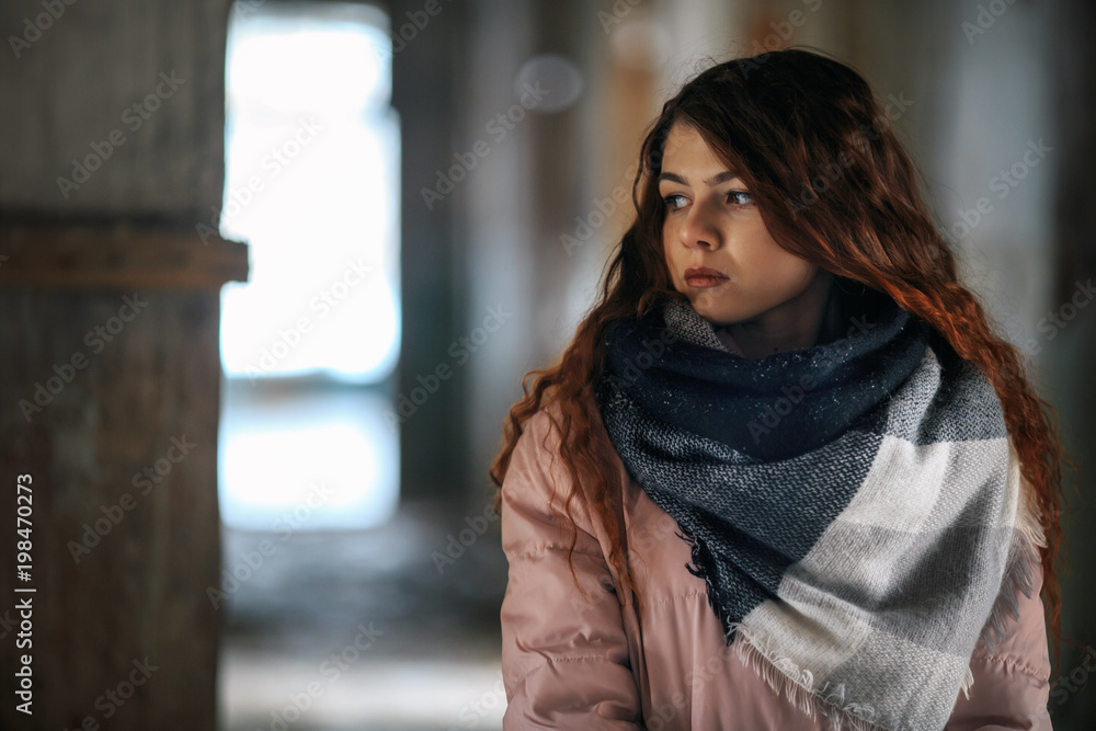 A young cute white girl in warm scarf and gloves is standing in the corridor of a ruined house in winter. Destroyed building. A young cute white girl in warm scarf and gloves is standing in the corridor of a ruined house in winter. Destroyed building.