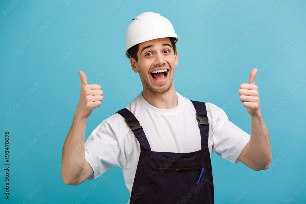 Cheerful screaming male builder in protective helmet showing thumbs up Cheerful screaming male builder in protective helmet showing thumbs up