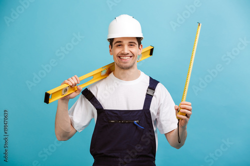 Print op canvas Happy male builder in protective helmet holding level tool