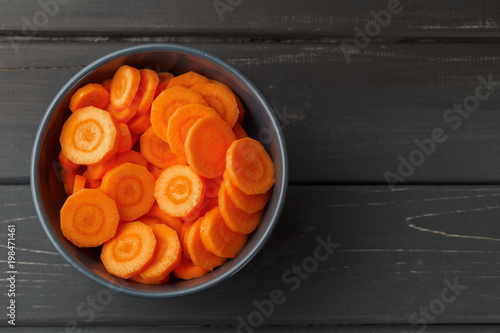 Sliced carrots in a bowl on black background