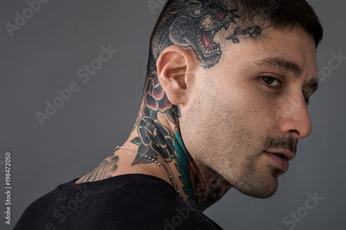 Handsome man with tiger and roses tattooed on neck and head