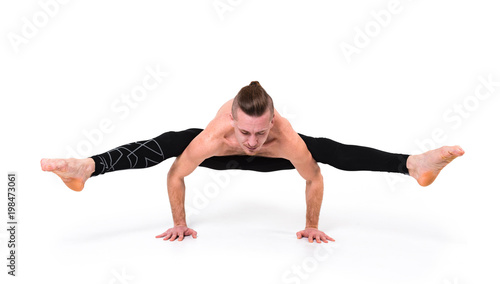 A young strong man doing yoga exercises - handstand. Studio shot isolated over white background