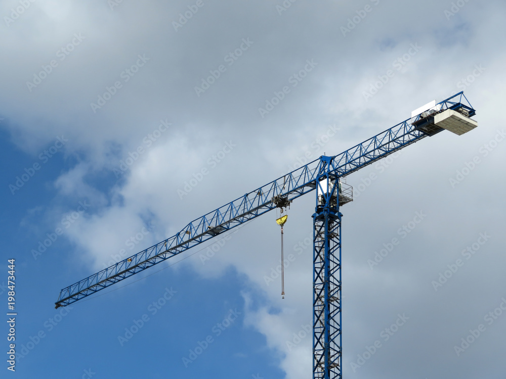 Construction crane against the cloudy blue sky
