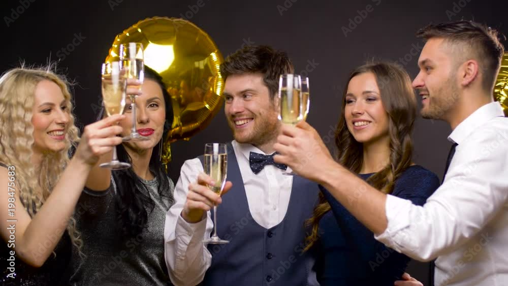 celebration, luxury and holidays concept - happy friends with golden balloons clinking champagne glasses at party over black background celebration, luxury and holidays concept - happy friends with golden balloons clinking champagne glasses at party over black background