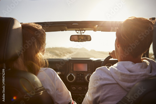 Young couple driving with sunroof open, rear passenger POV photo
