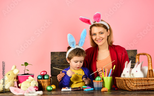 Mother and kid painting Easter eggs. Child holding basket with painted eggs.