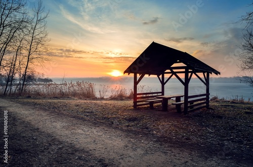 Beautiful morning by the lake. Wooden shed on the shore of a lake at sunrise.
