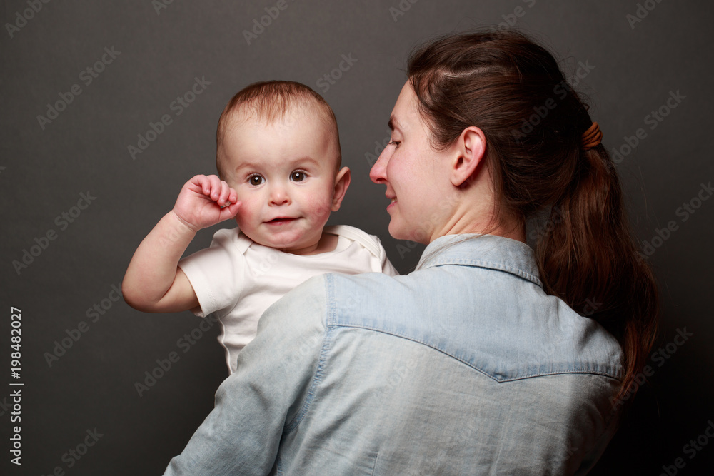 Mother and child hugging over gray background. Motherhood Mother and child hugging over gray background. Motherhood
