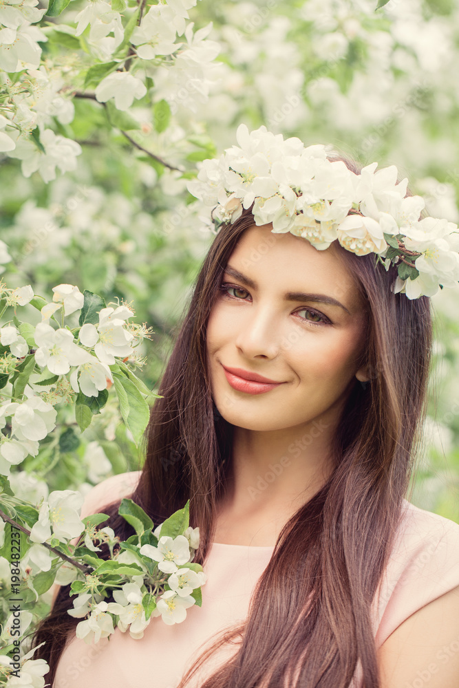 Fototapeta premium Beautiful Female Face Closeup. Beautiful smiling woman in spring flowers garden background