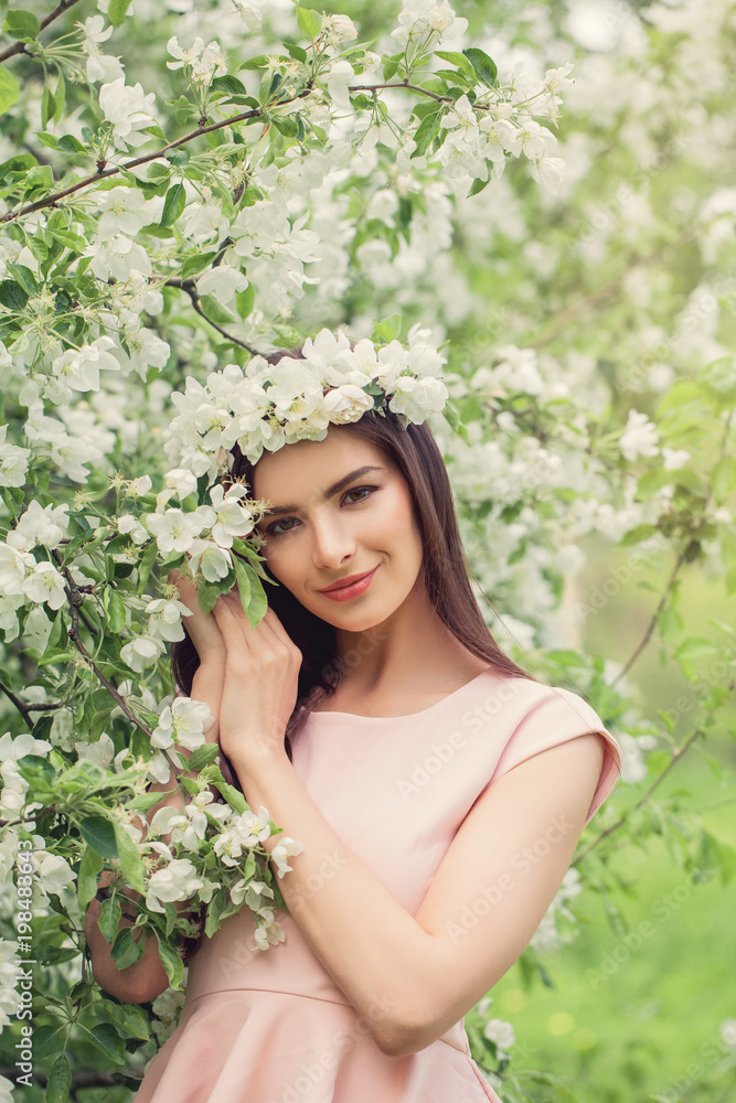 Spring woman outdoors on flowers background. Pretty young female model resting in blossom spring flowers garden Spring woman outdoors on flowers background. Pretty young female model resting in blossom spring flowers garden