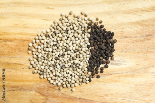 bunch of white and black peppercorns on a wooden kitchen board
