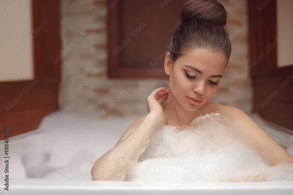 Young woman relaxing in foam jacuzzi bath spa, brunette enjoying the aromatherapy in wellness center. Beauty skin care treatment. Beautiful model relax in bathroom at home. Young woman relaxing in foam jacuzzi bath spa, brunette enjoying the aromatherapy in wellness center. Beauty skin care treatment. Beautiful model relax in bathroom at home.