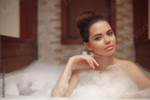 Skincare. Wellness. Young woman relaxing in jacuzzi bath spa  brunette enjoying foam bath in bathroom. Beauty skin care treatment. Beautiful model relax at home.