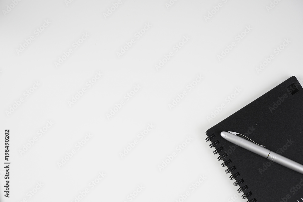 Flat lay image of black book and silver pen over white background Flat lay image of black book and silver pen over white background