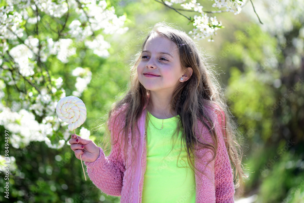 Schoolgirl walks outside near blooming trees. Kid in pink sweater Schoolgirl walks outside near blooming trees. Kid in pink sweater