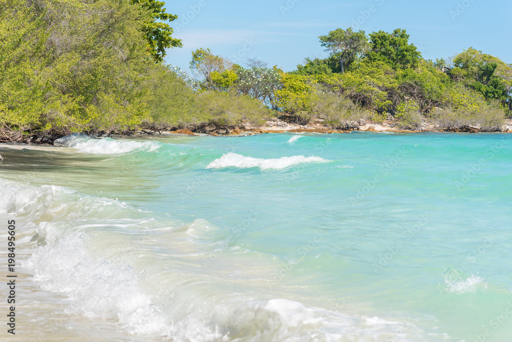 Obraz premium Crystal clear sea water of tropical beach of Ao Wai, Ko Samet (Koh Samed), Thailand in January. Aqua seascape with turquoise waves & lush trees in the background.
