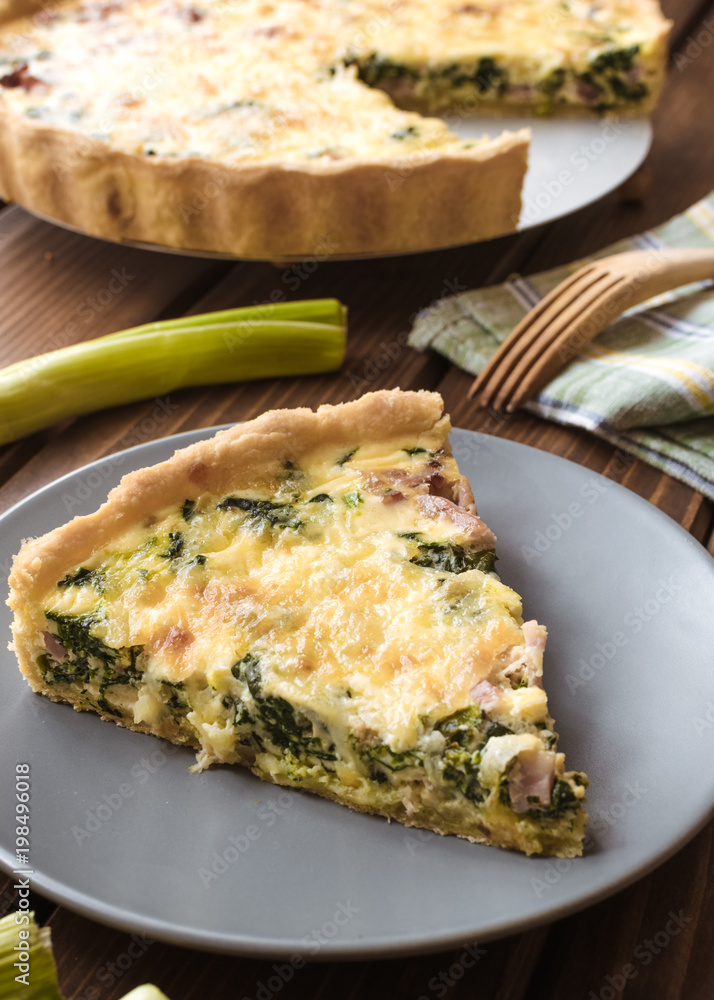 Spinach, onion and bacon tart on wood background