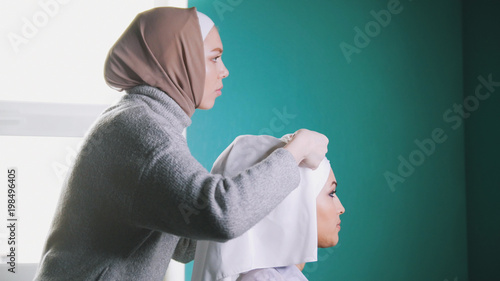 Muslim woman tying Islamic turban for attractive bride