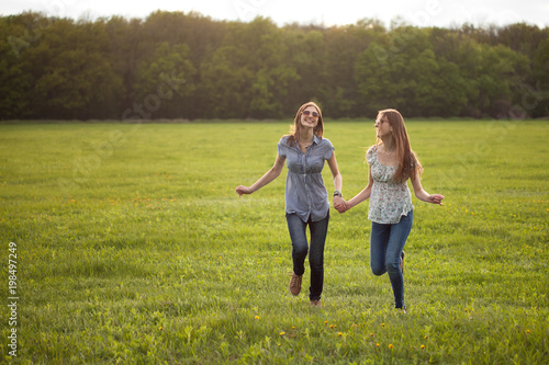 Two cheerful girl running on a lawn