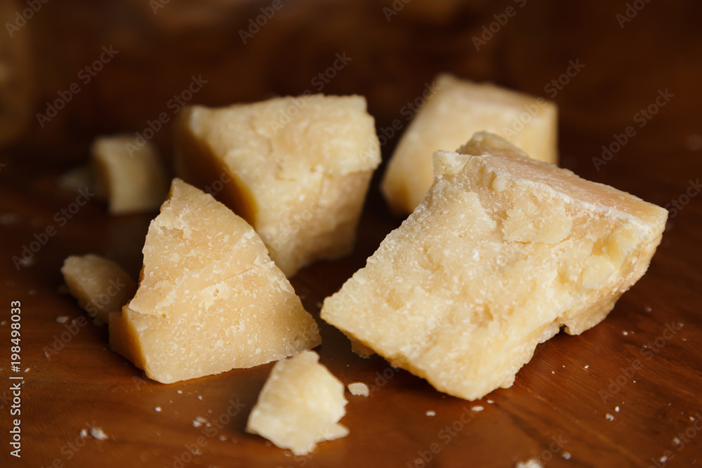 Parmesan cheese on a wooden board. Pieces of cheese close-up. Parmesan cheese on a wooden board. Pieces of cheese close-up.