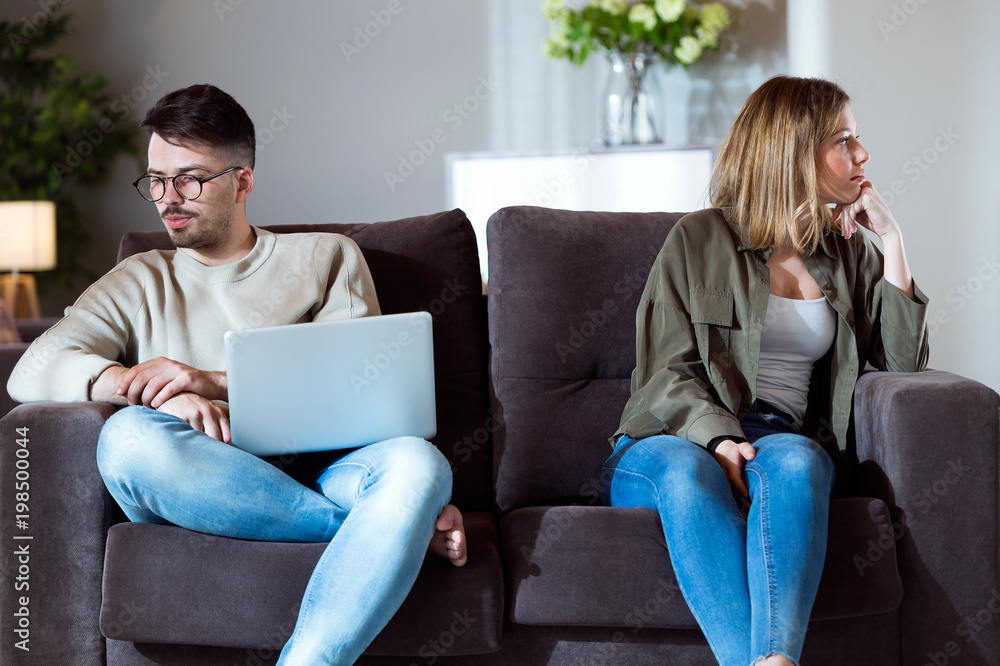 Angry young couple sitting on sofa together and looking to opposite sides at home. Angry young couple sitting on sofa together and looking to opposite sides at home.