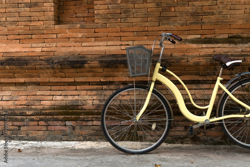 yellow bicycle parking near Thai traditional brick wall