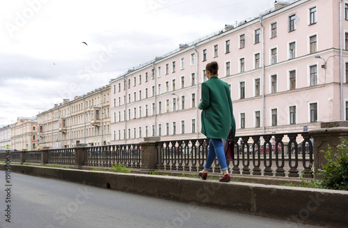 girl walks along the street in the city ,the building with lots of Windows