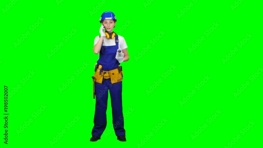 Builder is standing and talking on the phone with a drawing in her hands. Green screen Builder is standing and talking on the phone with a drawing in her hands. Green screen