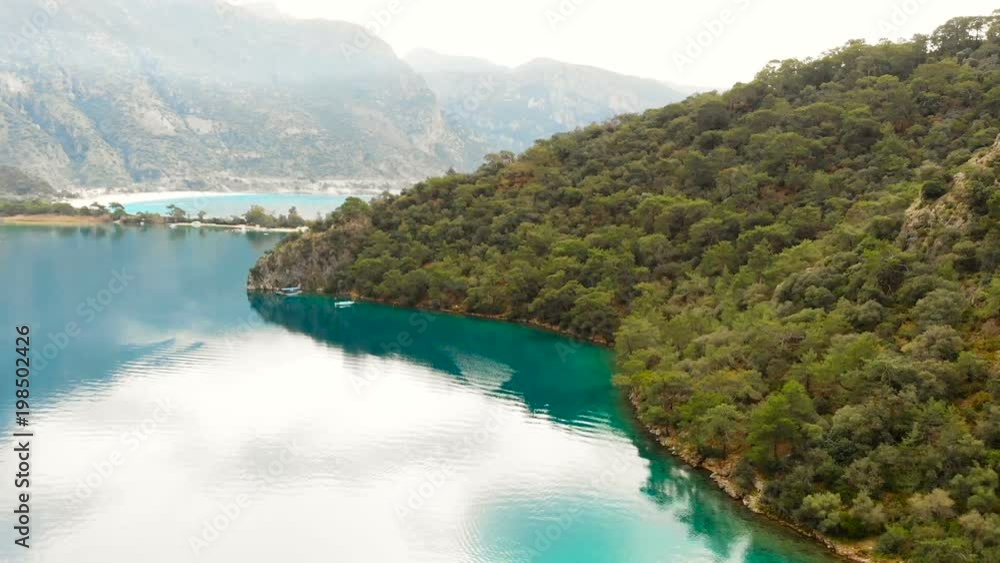 Aerial view over a calm lagoon with large mountains in the distance and thick forest on the coastline Aerial view over a calm lagoon with large mountains in the distance and thick forest on the coastline