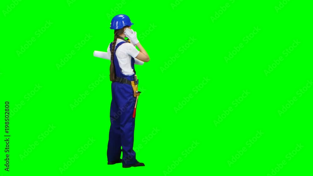 Builder is standing and talking on the phone with a drawing in her hands. Green screen Builder is standing and talking on the phone with a drawing in her hands. Green screen