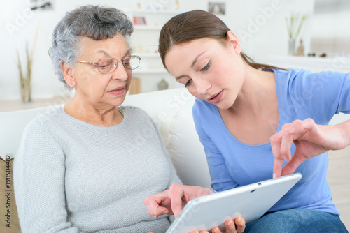 teenage granddaughter showing grandmother how to use digital tablet