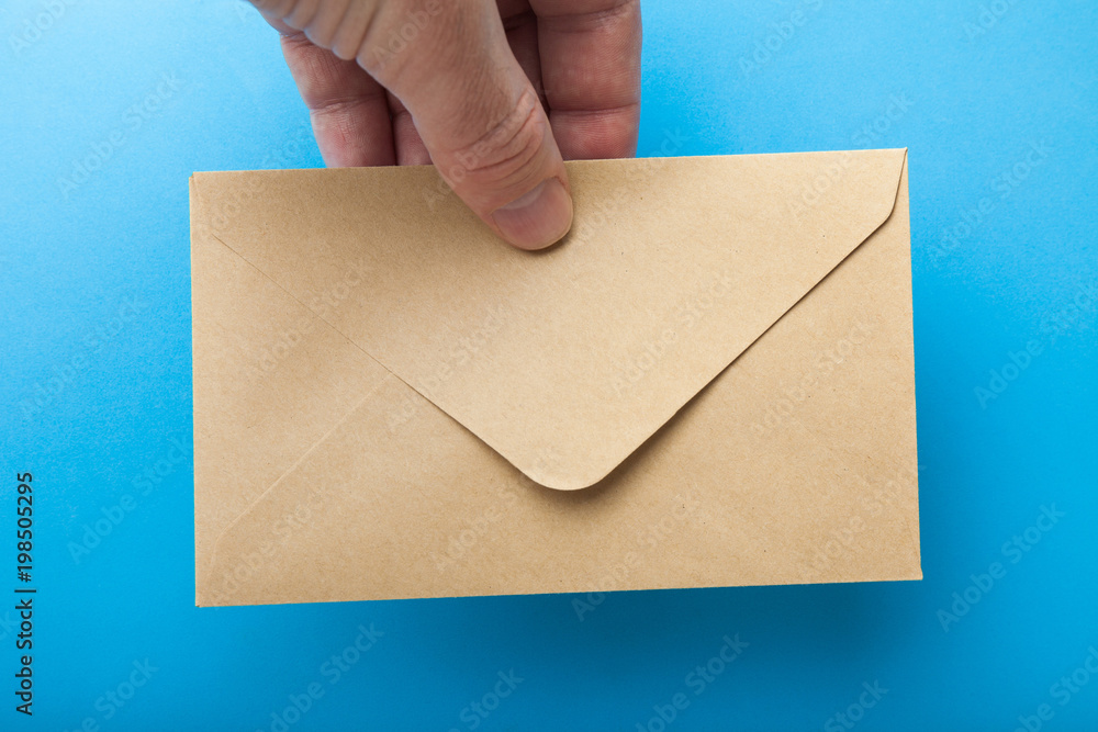 Mail envelope from recycled paper in a hand on a blue background. Mail envelope from recycled paper in a hand on a blue background.