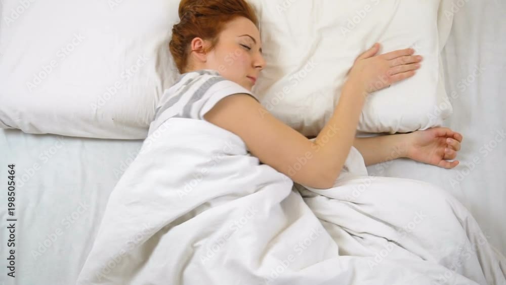 Foxy girl in T-shirt sleeping in bed moving and smiling in her sleep Foxy girl in T-shirt sleeping in bed moving and smiling in her sleep
