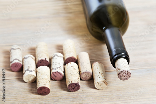 Glass bottle of red wine with corks on old wooden background. Closed bottleneck close up. Selective focus. Toned photo.