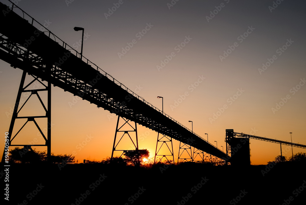 Silhouette of mining silo and conveyor belts at sunset