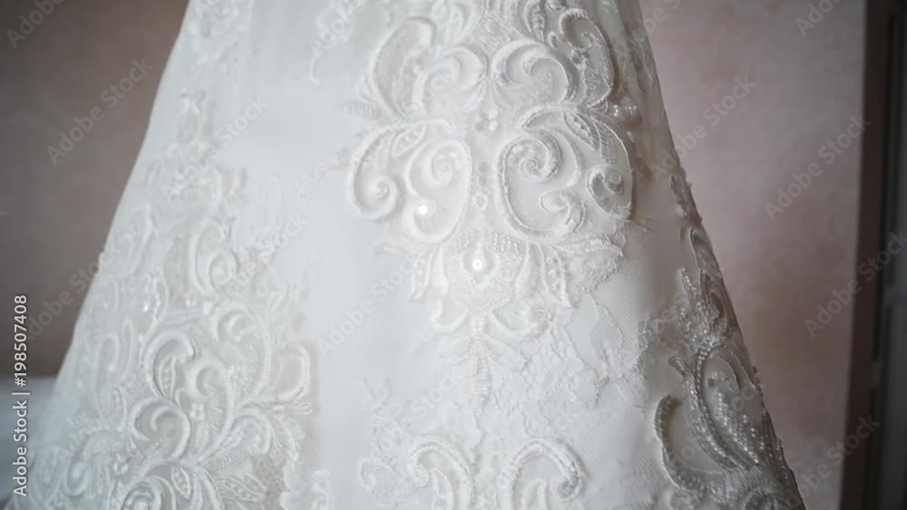 Bride's dress hanging on a lamp, wedding dress in bride's room, White wedding dress hanging. close up Bride's dress hanging on a lamp, wedding dress in bride's room, White wedding dress hanging. close up