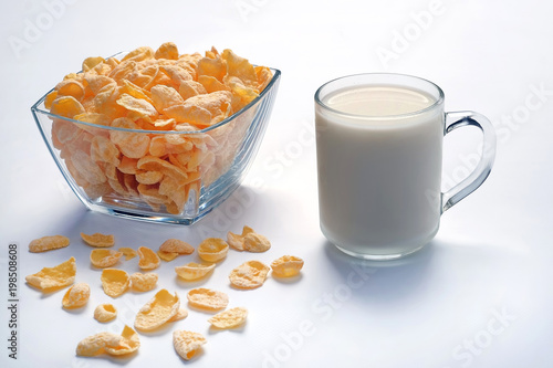 Bowl with cornflakes and cup with milk on light surface. Healthy food.