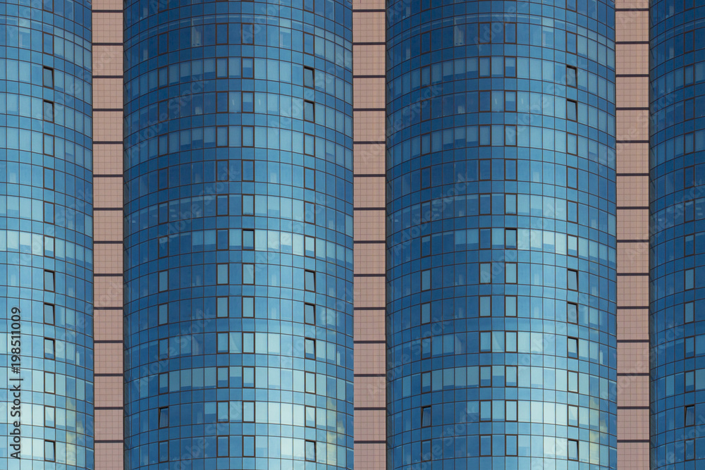 A multi-storey brick building under construction, against a blue sky background. High multi-story building. Skyscraper. Blue windows. Mirror