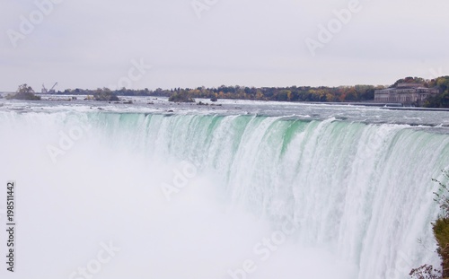 Beautiful and impressive panorama of the Niagara Falls in Ontario (Canada) on a bright colorful (red, orange, yellow) autumn day with water crashing down the falls onto rocks creating lots of mist