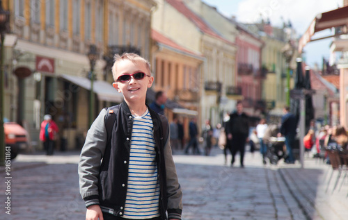 Cute blond boy in sunglasses in old european city