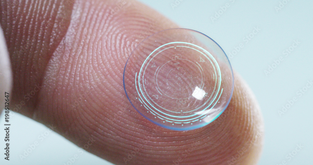 Macro shot of a finger holding a contact lens technology with a chip to see better in both eyes and increase diopters. Concept: eye examination, optical, immersive technology Macro shot of a finger holding a contact lens technology with a chip to see better in both eyes and increase diopters. Concept: eye examination, optical, immersive technology