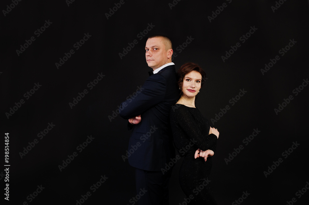 Elegance woman in black evening dress with man in suit posed on studio isolated on black. Duet couple of two.