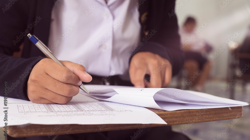 Close up to students writing and reading exam answer sheets exercises in classroom of school with stress.16:9 style Close up to students writing and reading exam answer sheets exercises in classroom of school with stress.16:9 style