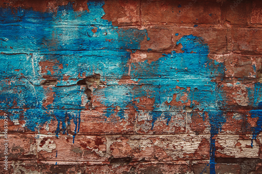 The old brick wall is faded with blue paint.