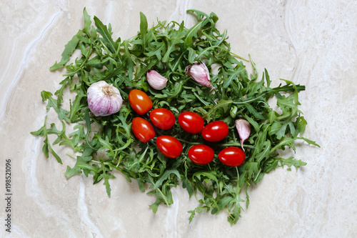 Rocket Arugula with plum tomatoes and garlic for Italian food on marble table