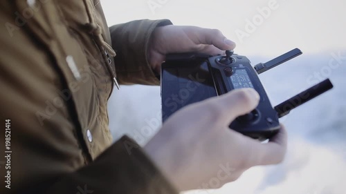 Man holds a drone remote controller in his hands. Pilot takes aerial photos and videos photo