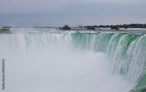 Tourist attraction: Beautiful and impressive panorama of the Niagara Falls in Ontario (Canada) on a bright colorful autumn day with water crashing down the falls onto rocks creating a lot of mist