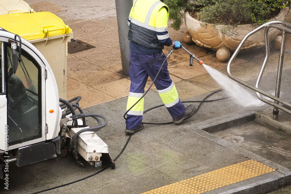 sweeper gardener cleaning the city street with pressure water sweeper gardener cleaning the city street with pressure water