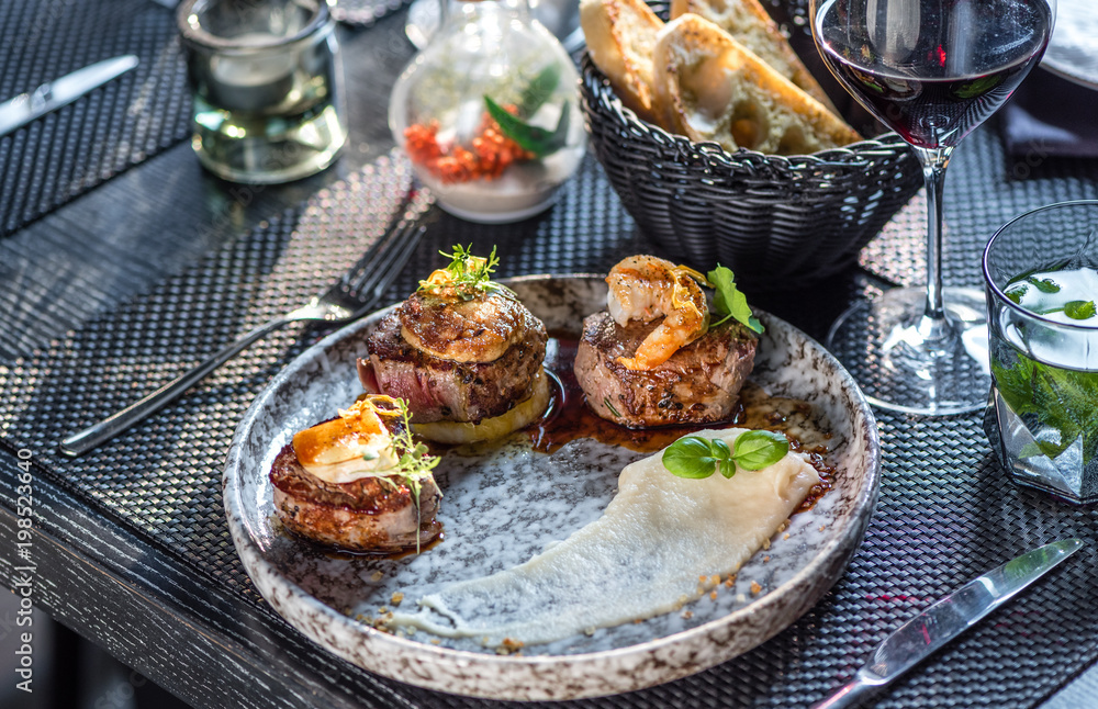Grilled steak meat with foie gras, shrimp, cheese and glass of red wine