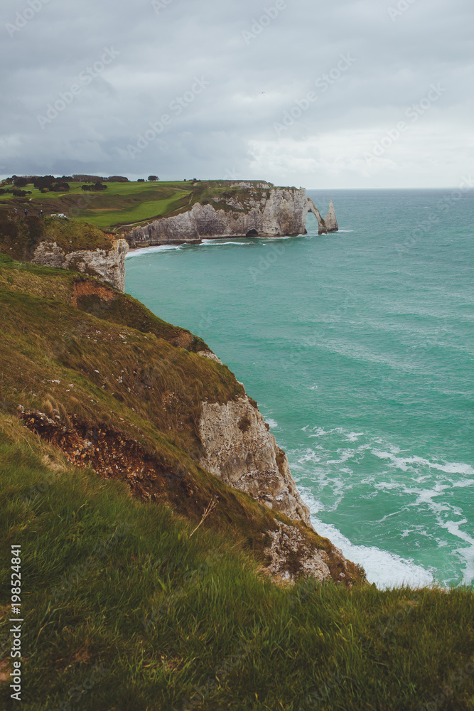 Colorful vertical limestone cliffs with sea coast  turquoise waters of the bay near Etretat in Normandy, France